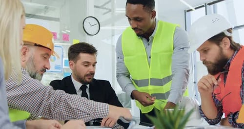 Engineer Explaining Building Details on Blueprint to His Serious High-Skilled Bearded Manager