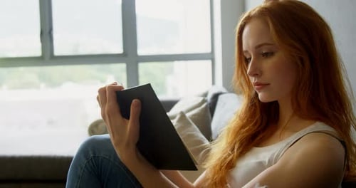 Woman Relaxes on Couch Using Tablet