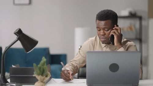 Young Adult Working at Desk, Taking Call
