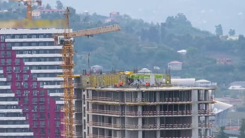 Hochbau. Zeitraffer. Turmdrehkran auf einer Baustelle hebt eine Last. Bauherren arbeiten