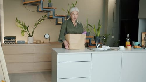 Woman Unpacking Groceries at Home in Kitchen