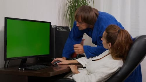 Businessman and Businesswoman in Home Clothes at Home with Green Screen Chroma Key PC on the Table.