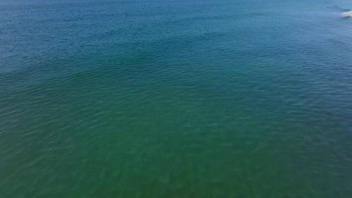 tilt up revealing the Oceanside Pier above green clear sea water. aerial view
