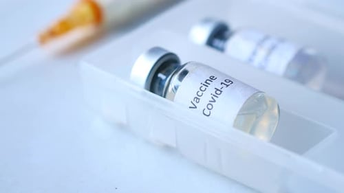 Nahaufnahme des Coronavirus-Impfstoffs in einer Schachtel und Spritze auf weißem Hintergrund