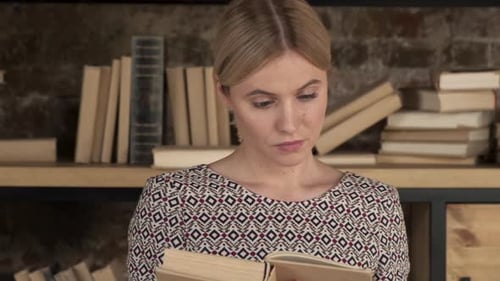Close up of the Caucasian young beautiful woman student in glasses reading a book