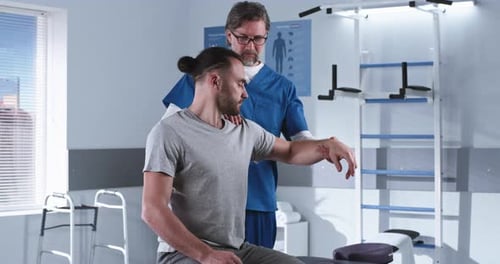 Rehabilitation Therapist Stretching Hand of Man