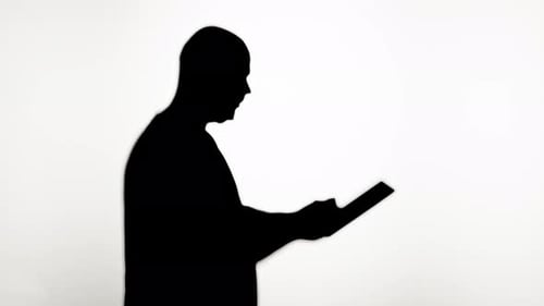 Silhouetted Adult Using a Handheld Tablet