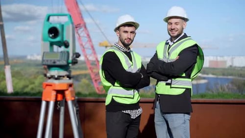 Portrait de deux jeunes ingénieurs confiants, mains croisées, regardant la caméra souriante debout