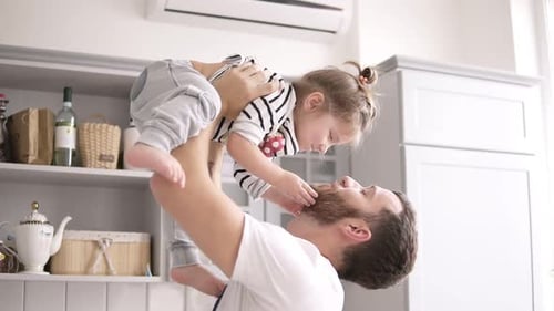 Loving Father Lifts Daughter Up in Home Kitchen