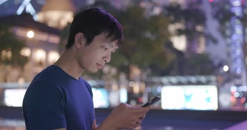 Man use of mobile phone in city at night