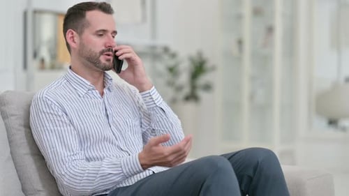 Man Answers Phone and Talks on Couch at Home