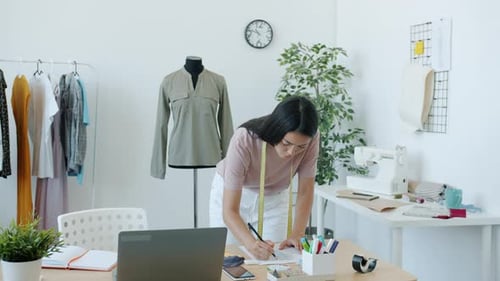 Fashion Designer Drawing Sketch in Bright Studio