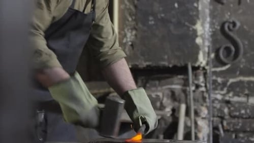 Bearded Blacksmith Shaping Hot Metal on Anvil