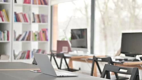 Man Sits at Desk, Types on Laptop in Office