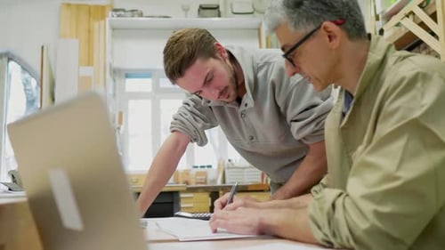 Un collègue aide un artisan à remplir la paperasse