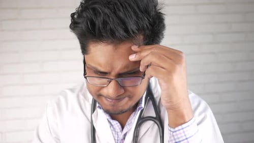 Worried Doctor with Hand on Forehead