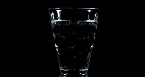 Sprudelndes Wasser in einem Glas vor schwarzem Hintergrund, Echtzeit 4K