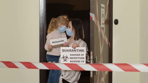 Mother and Child in Mask Hold Quarantine Signs