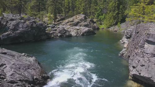 Luftdrohne bewegt sich über fließendem Wasser mit kleiner Felseninsel unter 4
