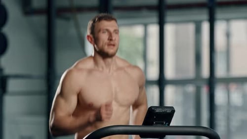 Muscular Man Running on Treadmill in Gym