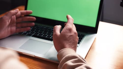 Young Caucasian Man at Home Office Sits Table Communicates Talk Speak with Green Screen Laptop