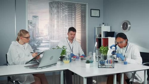 Mixed Race Team of Research Scientists Paying Attention at Collegue's Experiment with Liquid in
