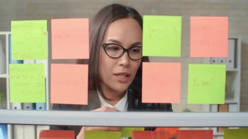 Woman Brainstorms with Sticky Notes in Modern Office