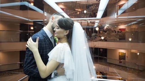 Bearded Groom in a Suit Kisses His Pretty Bride in a Wedding Dress, Riding in a Cozy Beautiful