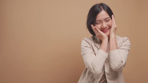 Une femme d'affaires asiatique heureuse se sent timide debout avec un espace de copie isolé sur fond beige