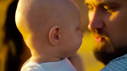 Happy Father Holds Baby at Sunset