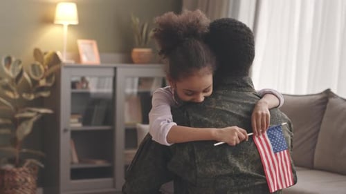 Touching Reunion: Child Embraces Soldier with American Flag