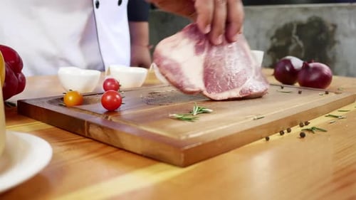 Chef cook season fresh chunk of deli piece of beef with sea salt and grounded spicy peppers.