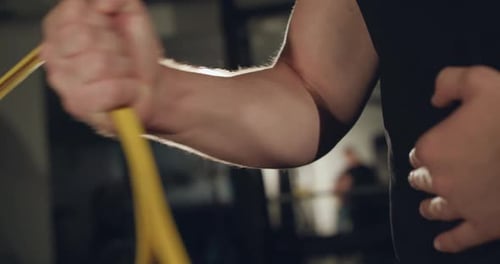Closeup of Man in Glasses Pulling Loop with Hand at Simulator in a Dark Gym