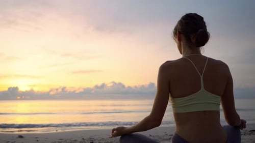 Woman Meditating on Beach at Sunrise