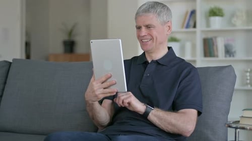 Man Sitting Using Tablet Celebrates Success