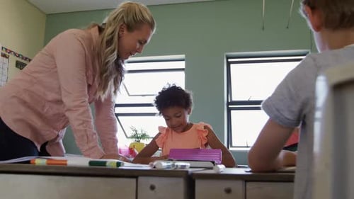 Teacher Assisting Young Student at School Desk