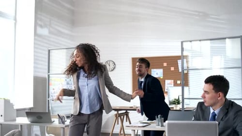 Joyous Coworkers Dancing in Conga Line in the Office
