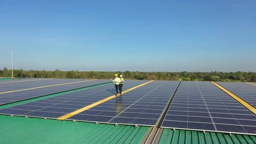 4K Professional engineer using tablet maintaining solar cell panels together on building rooftop.