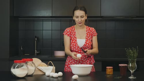 Woman Cracking Eggs in Dark Modern Kitchen