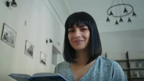 Happy Woman Reads a Book in the Library Chooses Books From the Shelf