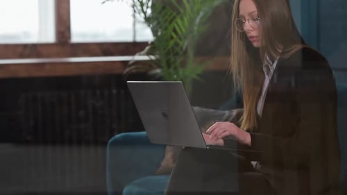 Portrait of an Elegant Businesswoman Sitting with Laptop on the Couch at the Luxury Blue Office