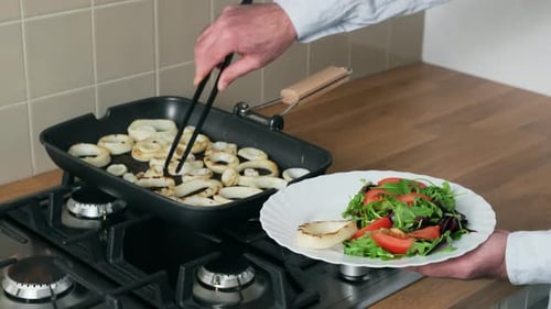 Rings of calamari are frying in grill pan in kitchen