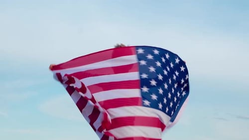 Child Running with American Flag in Blue Sky