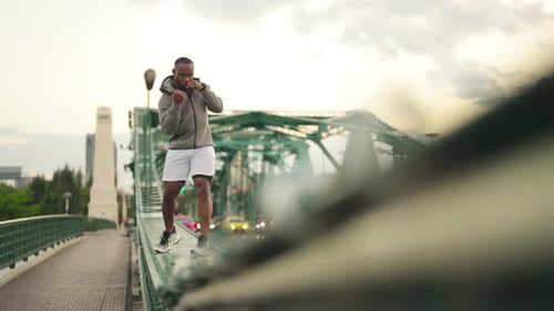 4K African man in sportswear do sport training boxing exercise in the city at summer sunset.