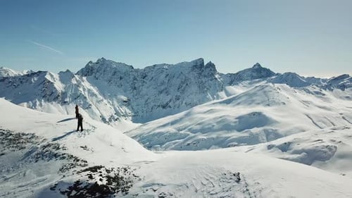 Aerial drone view of a skier skiing on top of a snow covered mountains in the winter