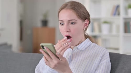 Shocked Woman Looking at Her Phone in a Room
