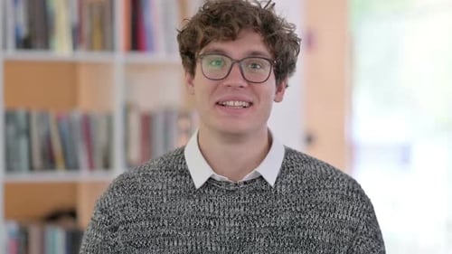 Young Man Waving and Speaking to Camera