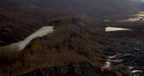 Aerial helicopter over pond, swans resting in water, tilt up to see mountain, golden hour drone foot