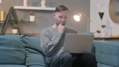 Casual Manwith Laptop Thinking on Sofa
