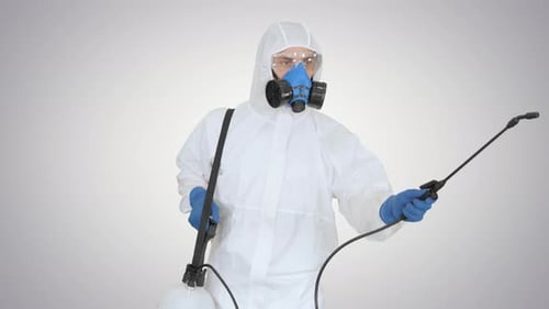 Mann in einem Gefahrgut geht herein und benutzt Desinfektionsmittel auf Gradientenhintergrund
